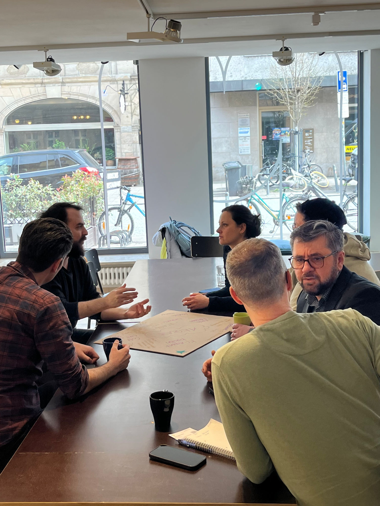 Sich angeregt an einem Tisch unterhaltende Gruppe Menschen.